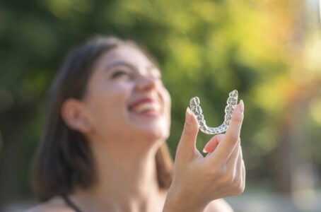 Beautiful smiling Turkish woman is holding an invisalign aligner in alpha nj 