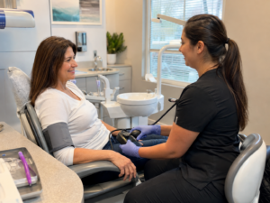 Dental professional checking an adult patient’s blood pressure before a dental visit.